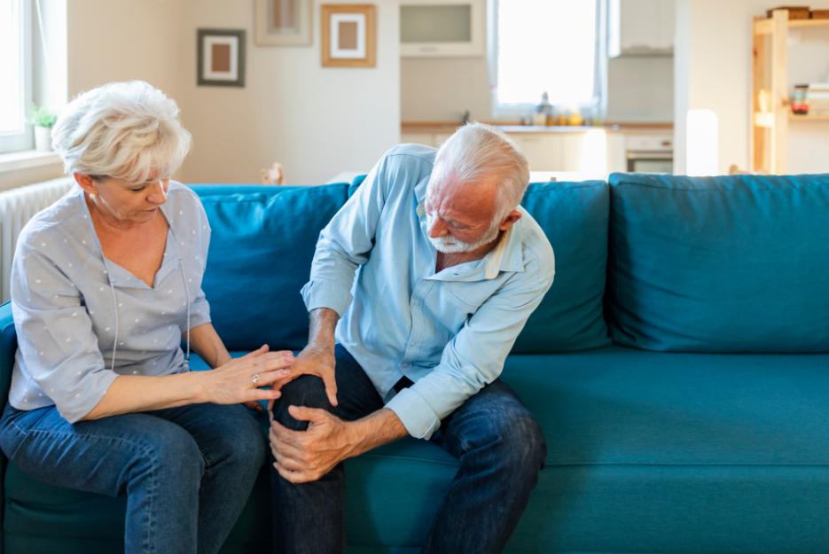 arthritis pain in the knees displayed by an older couple with the husband gripping his right knee from pain