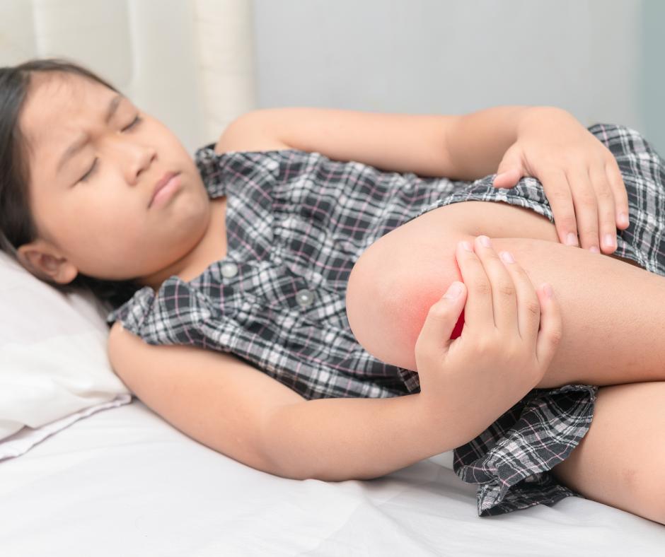 Young girl holding her left front knee from pain radiating, possible cause of pain from Osgood Schlatter's Apophysitis or Growing Pain in Knees